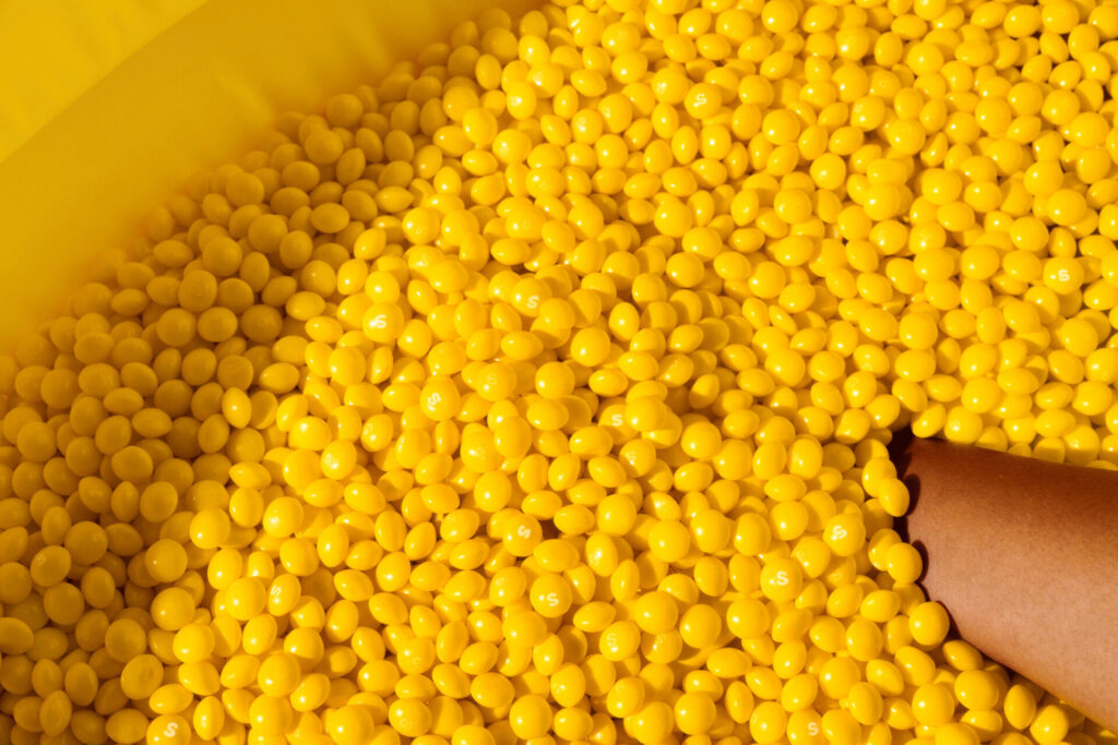 A person is reaching into a bowl of yellow candy, undisturbed by the weather outside.