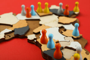 Wooden puzzle map with colorful game pawns representing different territories of the BRICS Alliance, set against a red background.